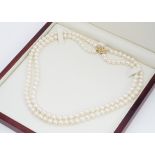 A double string of cultured pearls, of uniform size on a 9ct gold pierced clasp, 22cm together, with