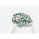 An Edwardian style emerald and diamond platinum dress ring, the three old cuts surrounded in a