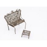 A continental white metal filigree miniature sofa and footstool, possibly from a dolls' house and
