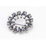A contemporary white metal diamond and sapphire circular brooch, the mixed cut circular claw set