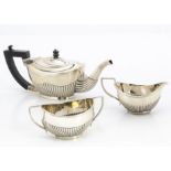 An associated late Victorian three piece silver bachelors tea set, oval with half fluted bodies,