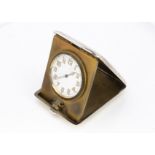 An Art Deco period silver travel clock, the manual wind dashboard style clock in folding case,