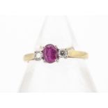 An 18ct gold ruby and diamond three stone ring, the white claw set mixed cut oval flanked by a
