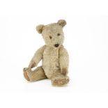 A post-war Chiltern Hugmee teddy bear, with blonde mohair, orange and black glass eyes, black