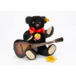 A Steiff yellow tagged Bobby Musical Teddy Bear, black with guitar, in original box, 1993 (slight