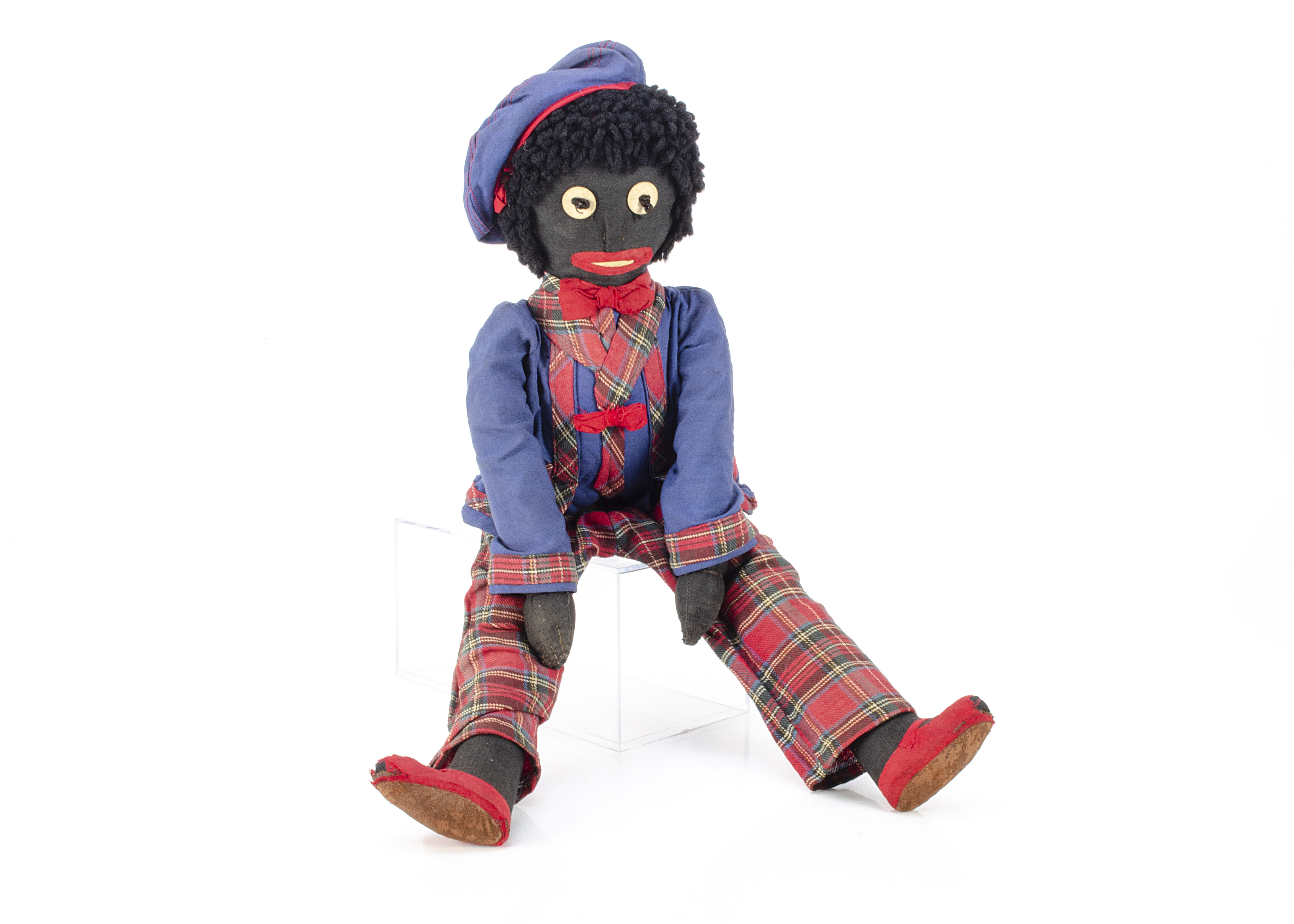 A British 1920s Golly dressed in tartan, with black cloth head and body, with white linen eyes