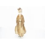 A mid 19th century German dipped wax over composition doll, with moulded hat, inset dark glass eyes,