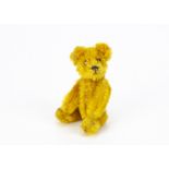A Schuco miniature teddy bear 1950s, with golden mohair, metal eyes, black stitched nose and mouth