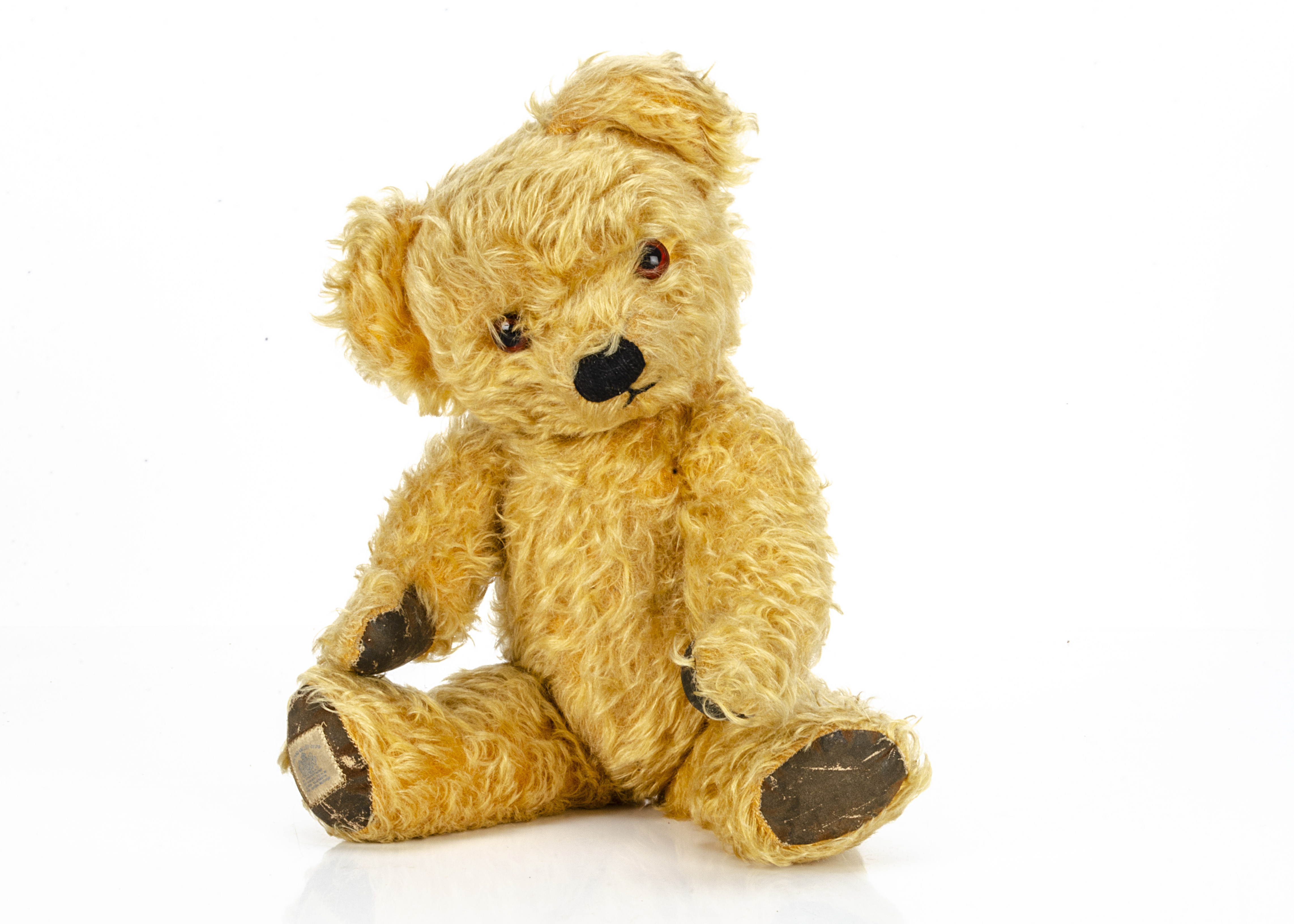 A post-war Chad Valley teddy bear, with golden mohair, orange and black glass eyes, black stitched