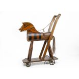A varnished wood push-along horse on wheels, simply constructed with cylindrical body with glass