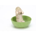 A Gebruder Heubach bathing girl, kneeling with hands washing hair in large green glazed basin and