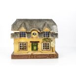 A Small German dolls' house thatched cottage, cream painted with stencil stone effect, textured