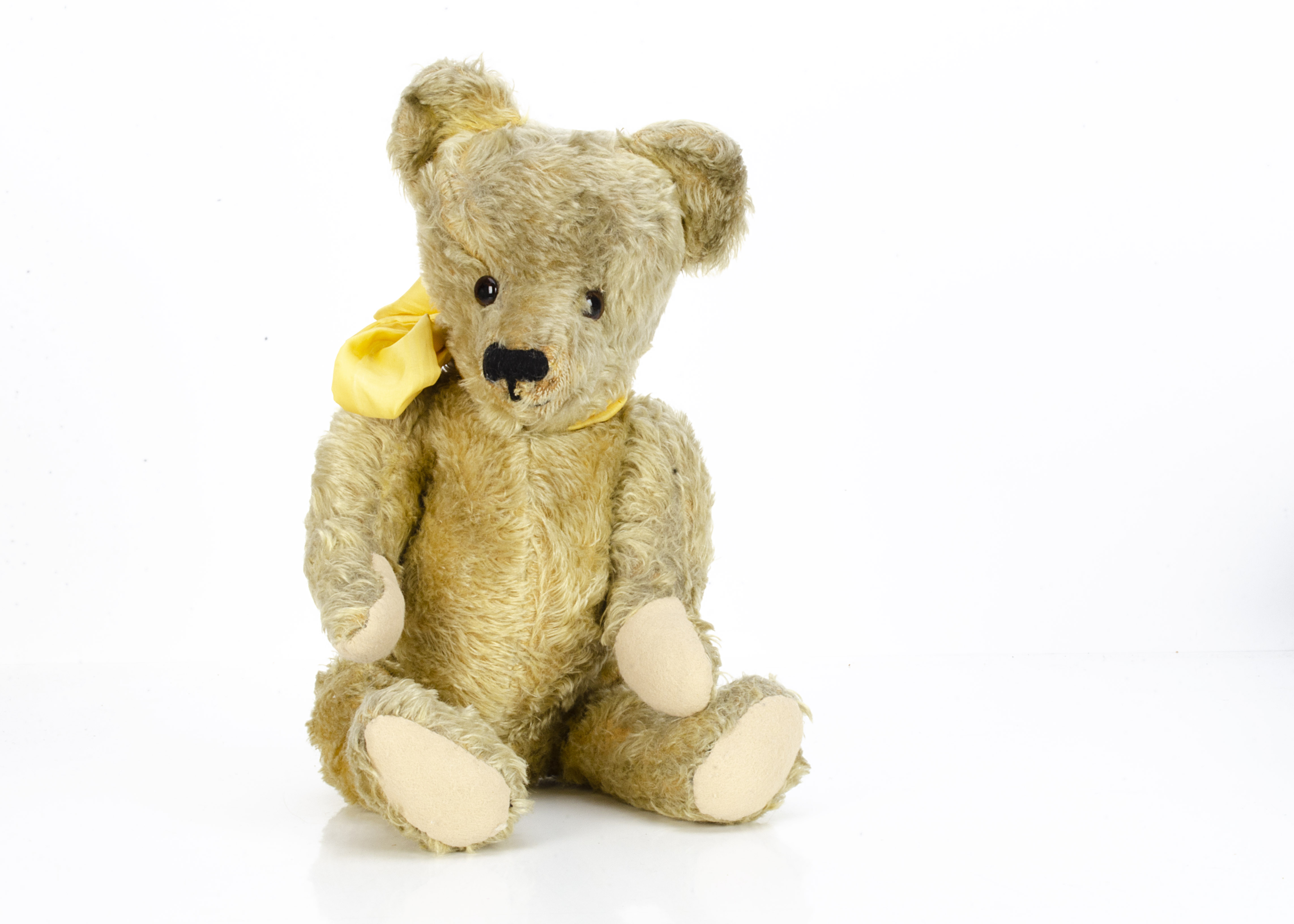 A 1930s British teddy bear, with golden mohair, orange and black glass eyes, pronounced muzzle,