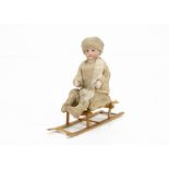 A bisque head boy sledging candy container circa 1910, probably with Gebruder Heubach head with