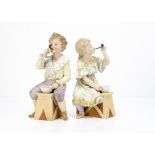 A pair of Gebruder Heubach bubble blowers, the boy seated across a wood bench in pale yellow and