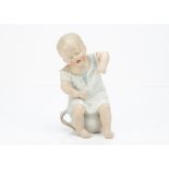 An unusual Gebruder Heubach baby seated on chamber pot, in nightshirt with sad face, unusual jointed