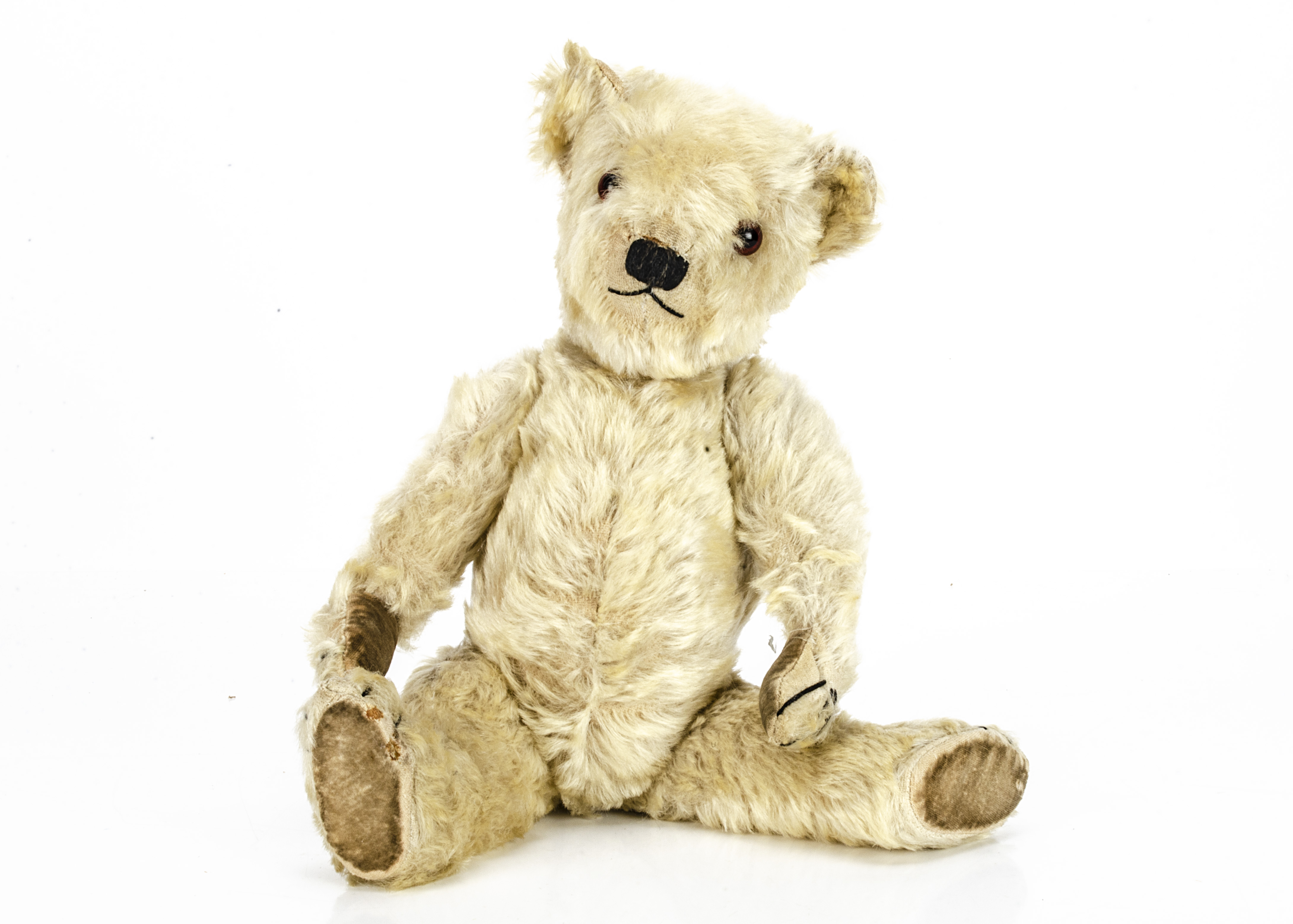 A 1930s Chiltern white mohair teddy bear, with orange and black glass eyes, black stitched nose,