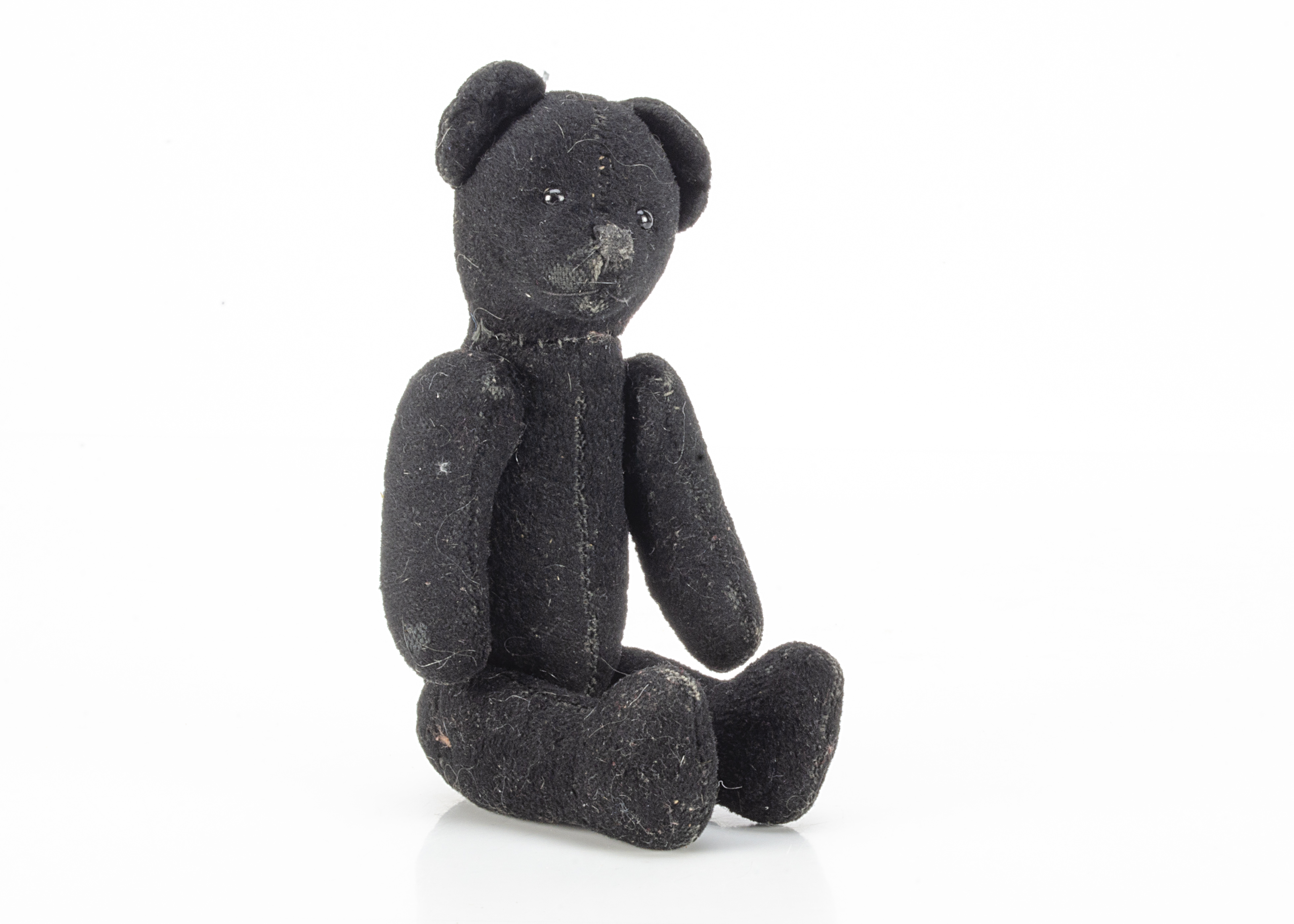 An unusual small black teddy bear, possibly Russian with short velvet like plush, black glass