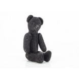 An unusual small black teddy bear, possibly Russian with short velvet like plush, black glass