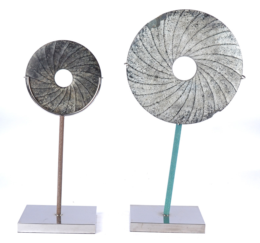 Two abstract stone disc forms on faux green and chrome type bases, diameter 21cm.