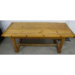 A contemporary pine refectory table, plank top raised on turned supports untied by an H stretcher,
