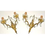 A pair of gilt metal and glass wall lights, each with two branches supporting floral bowls,