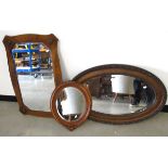 Three framed wall mirrors, two oval and one rectangular all with bevelled glass.