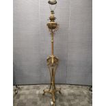 An Edwardian tall brass standard lamp,with ornate supports and decoration, converted and for