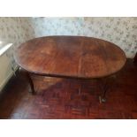 A 1920's oval mahogany wind out dining table, with a leaf on cabriole supports, and winding