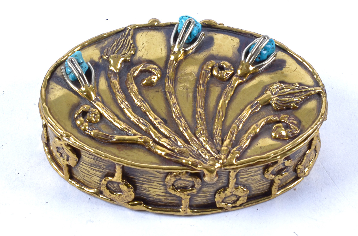 An Arts & Crafts polished brass oval box, with floral decoration and inset with stones, hinged