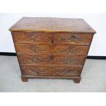 An 18th Century oak chest, of two short over three long graduated drawers, later carving to panelled