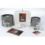 Four Swarovski Crystal figures of deer, one laying down, the others standing, two with antlers,