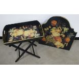 A contemporary butlers tray on stand, black with gold edging and decorated with a fruit and