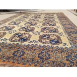 A 20th Century woollen rug with geometric shapes and motifs on a tan ground, blue and red