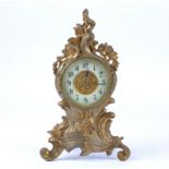 A late 19th or early 20th Century gilt metal mantel clock raised on four scrolling feet, the