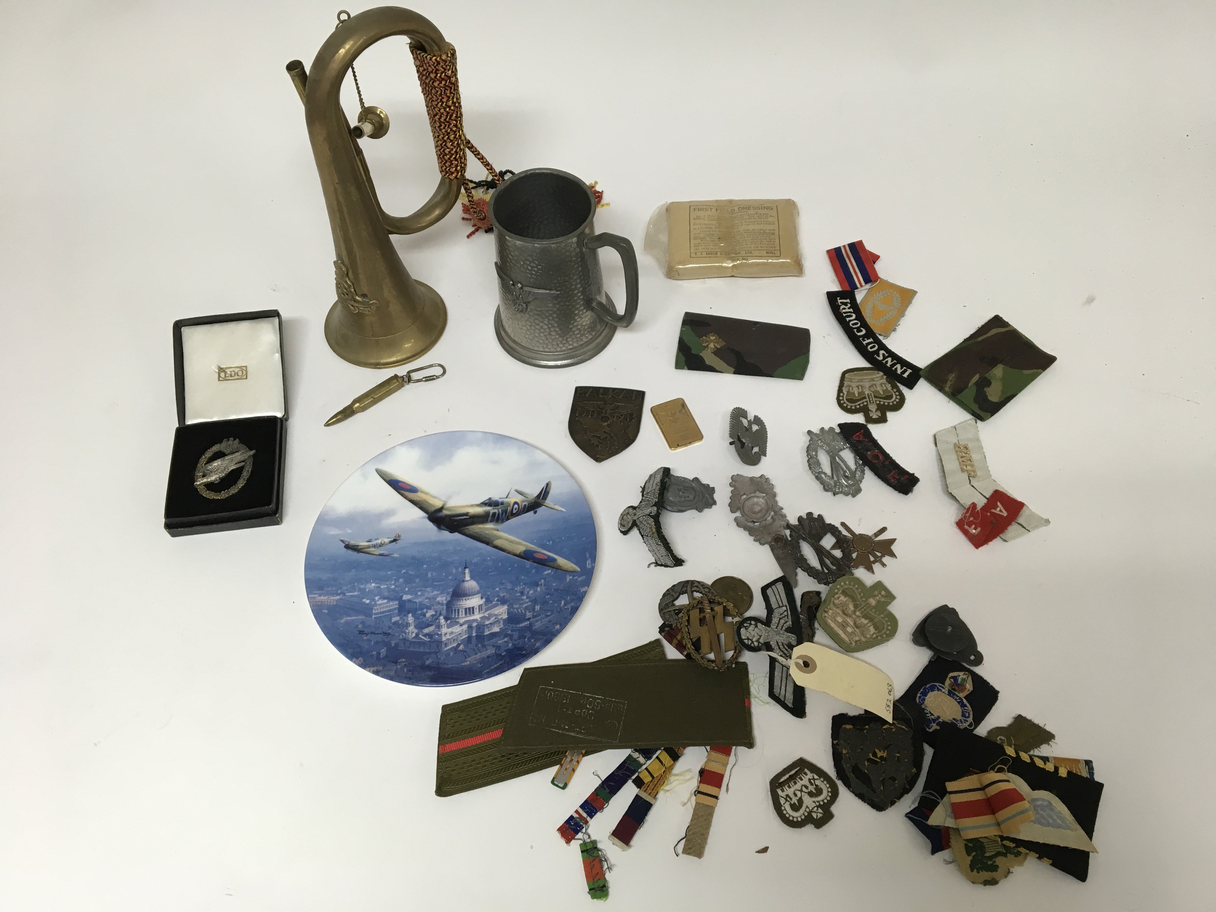 A group of military badges and patches, including some oddments such as a tankard, a bugle and