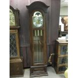 A modern oak longcase clock with arch top, rotating dial and visible pendulum, approx height 201cm.