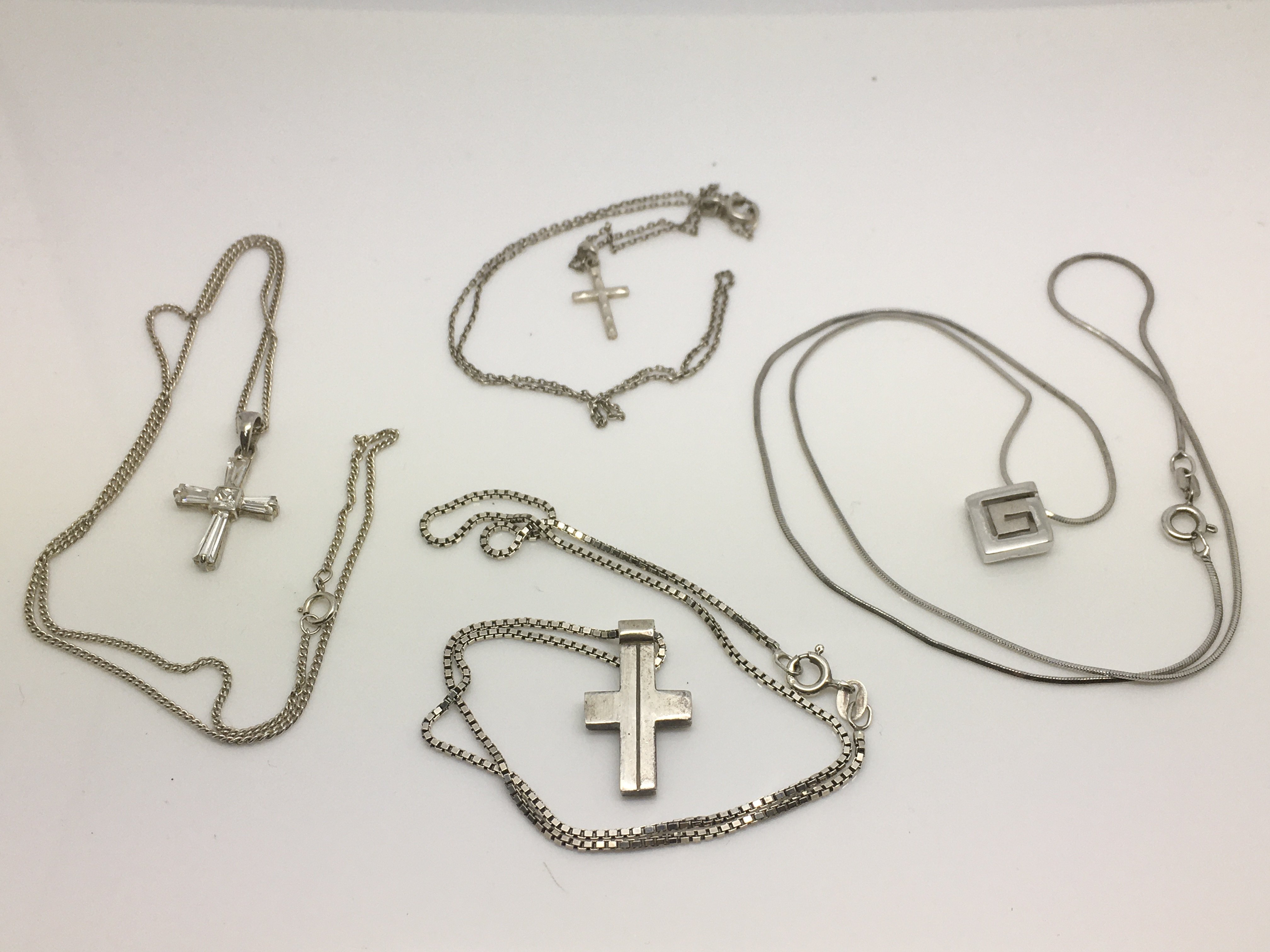 Four silver necklaces comprising three crucifixes