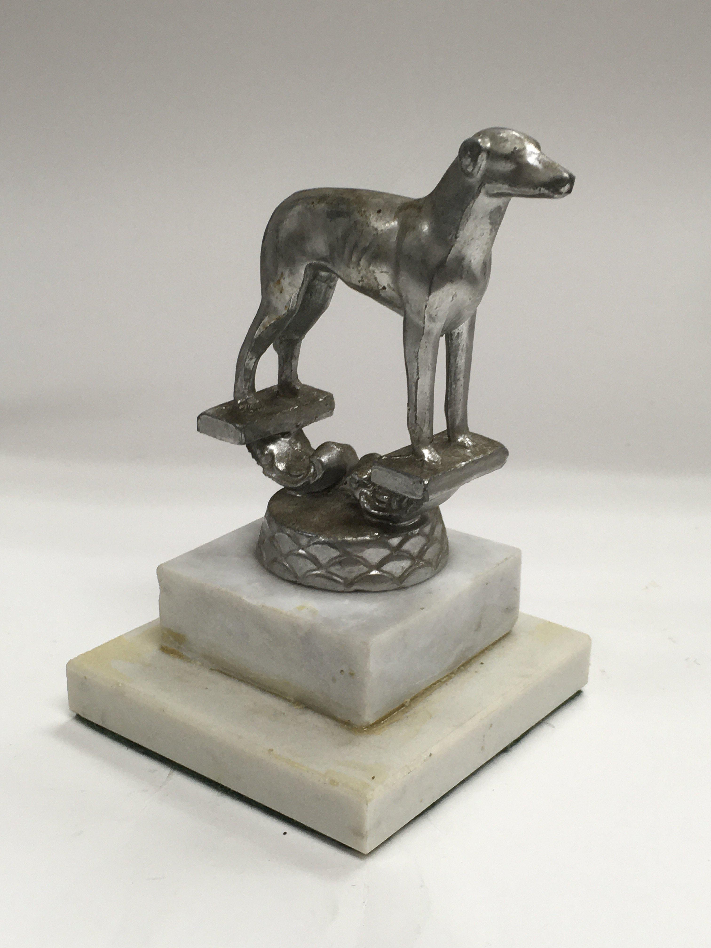 A small car mascot on the form of a greyhound rais