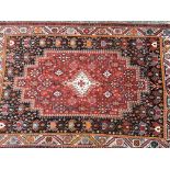 Two handed knotted rugs one with a tomato red fiel