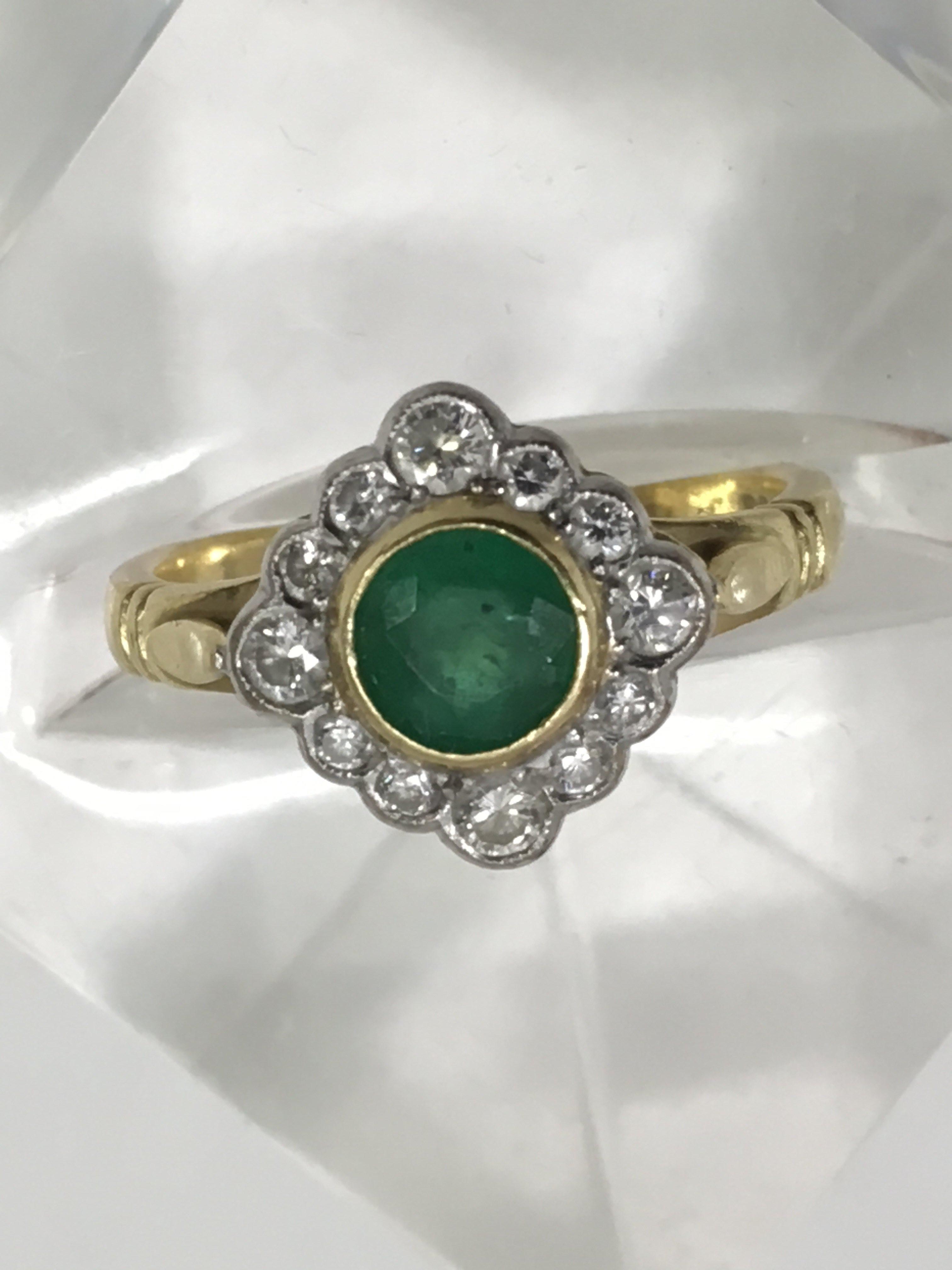 An 18ct gold ring set with central emerald in diam