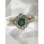 An 18ct gold ring set with central emerald in diam