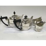 A silver four piece conforming tea set with ebony