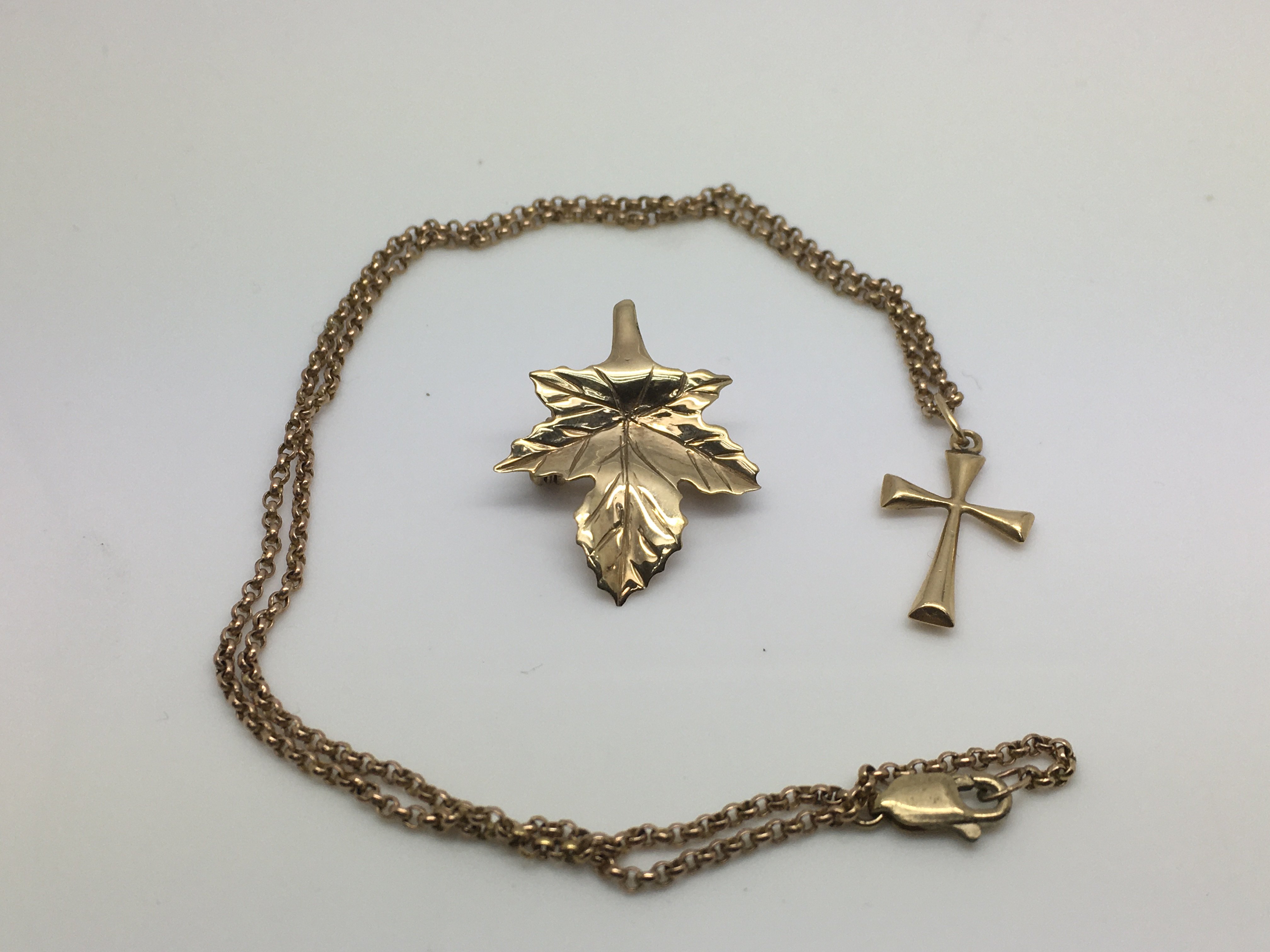 A gold brooch in the form of a leaf and a gold cru