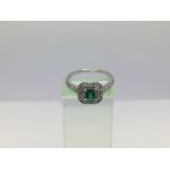 An 18ct white gold ring set with a central emerald