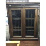 An oak bookcase with lead light panels.