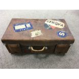 A vintage leather suitcase bearing travel labels