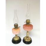 Two brass oil lamps with peach glass reservoirs, a
