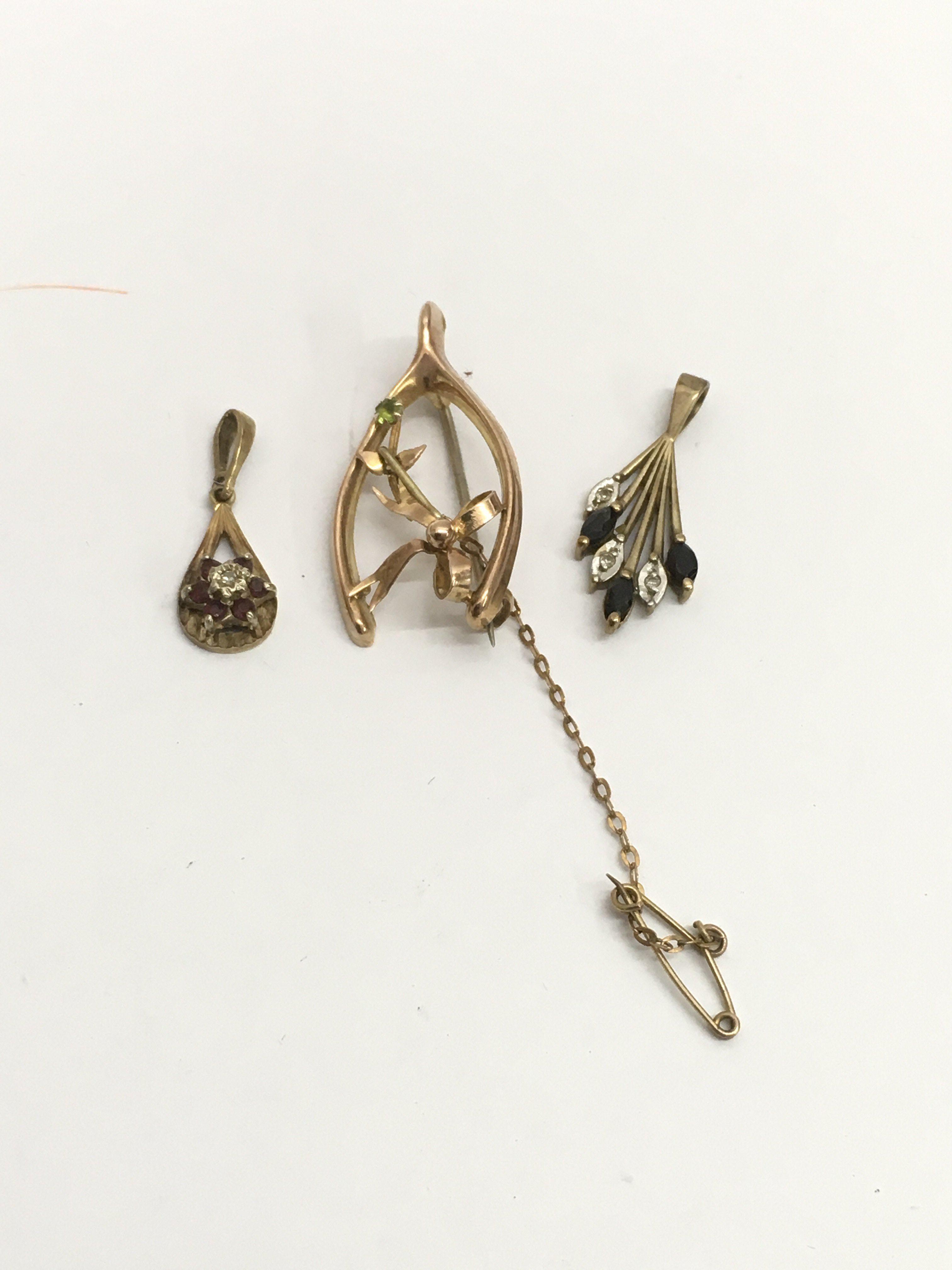 A 9ct gold wishbone brooch and two 9ct gold stone