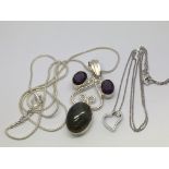 A silver pendant set with 3 coloured stones on a c